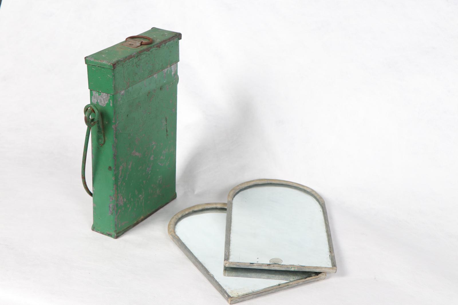 Green tin box with two curved mirrors next to it.