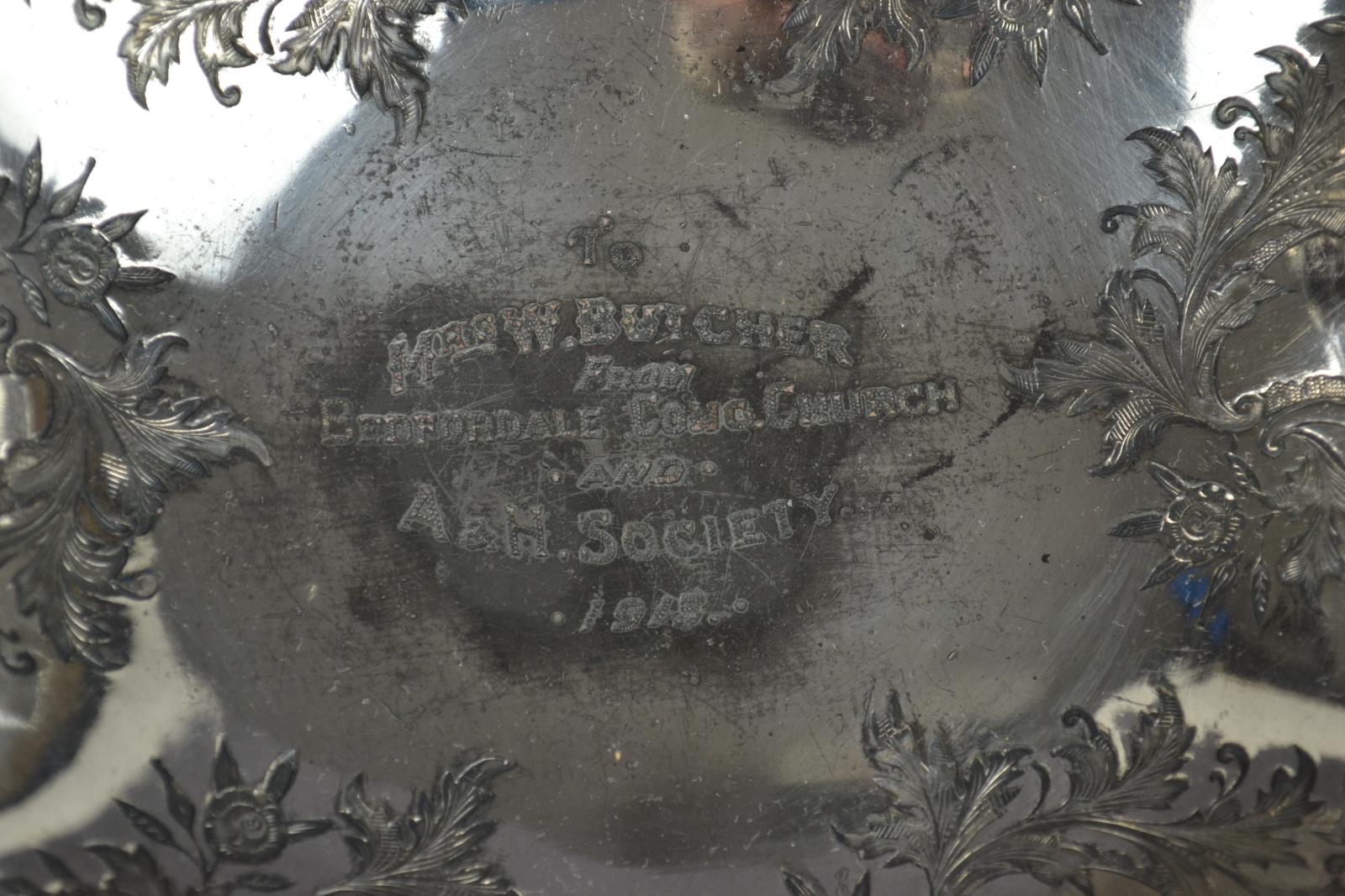 close up of engraved inscription on reflective metal surface. Inscription 'To / MRS W. BUTCHER / FROM / BEDFORDALE CONG. CHURCH / AND A&H. SOCIETY / 1913'