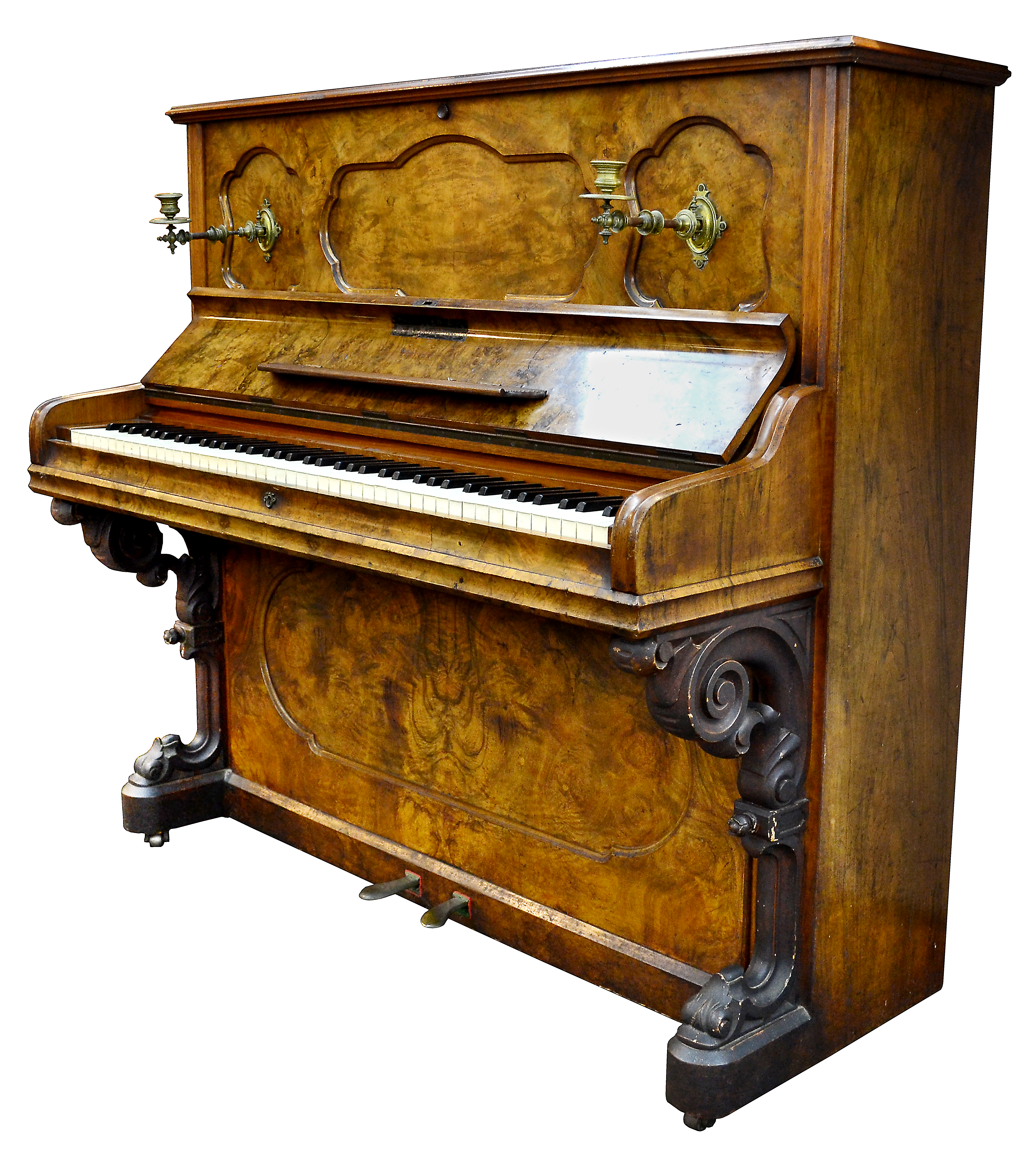 Upright wood paneled piano, cover opened to reveal row of white and black keys. Above the keys are two brass candle holders. 