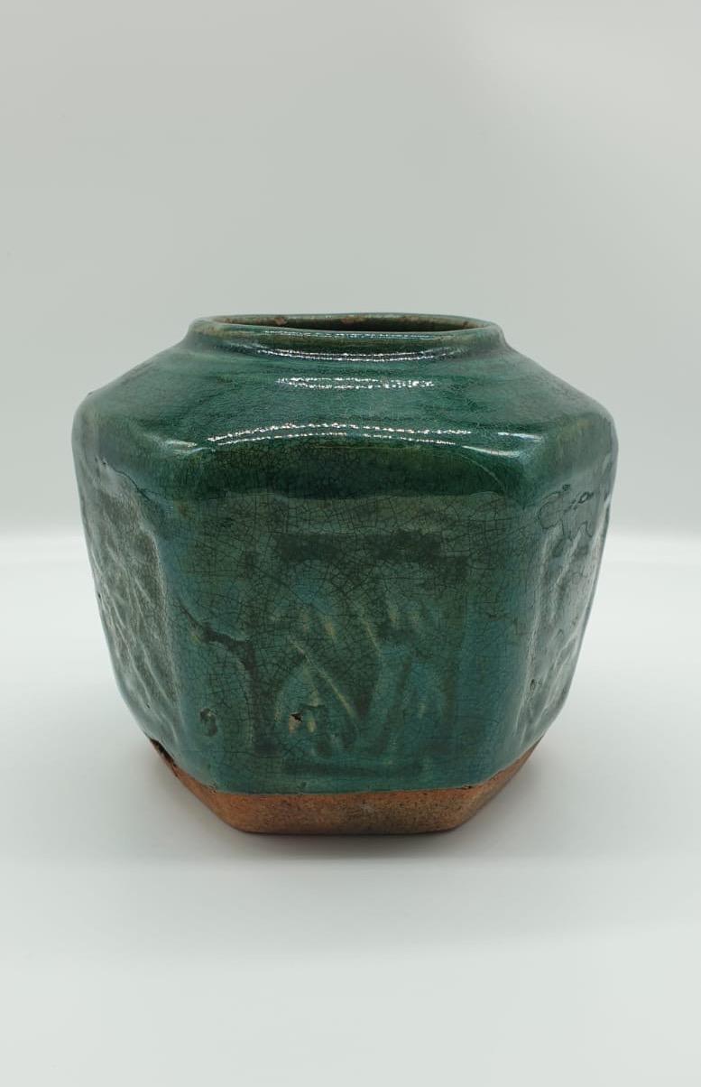 Earthenware vase with a green glaze sitting on a white background