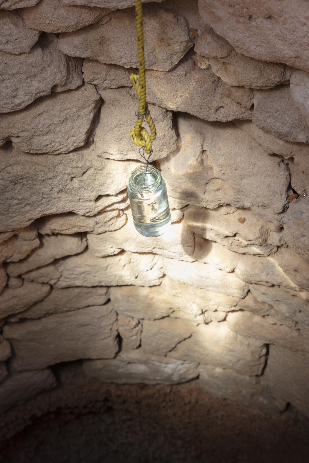 Jar on rope against sides of well.