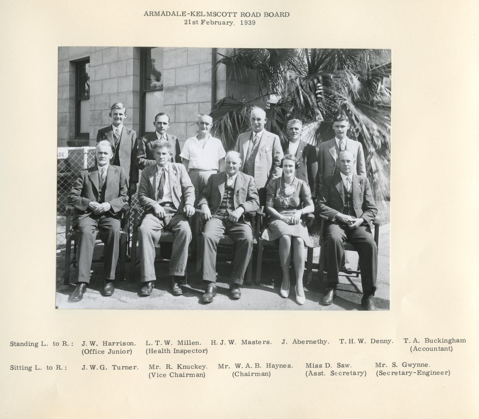 Official photograph of the 1939 Armadale Kelmscott Roads Board councillors and staff. Features two rows of mainly men with the back row standing and the front row sitting on chairs. Daphne Saw, the only woman in the photo is sitting second from the right.