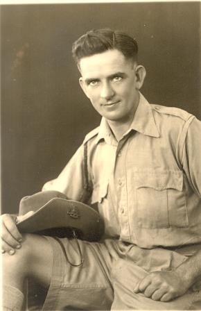 male, wearing short sleeved collared shirt with matching shorts, Australian military slouch hat resting on right leg