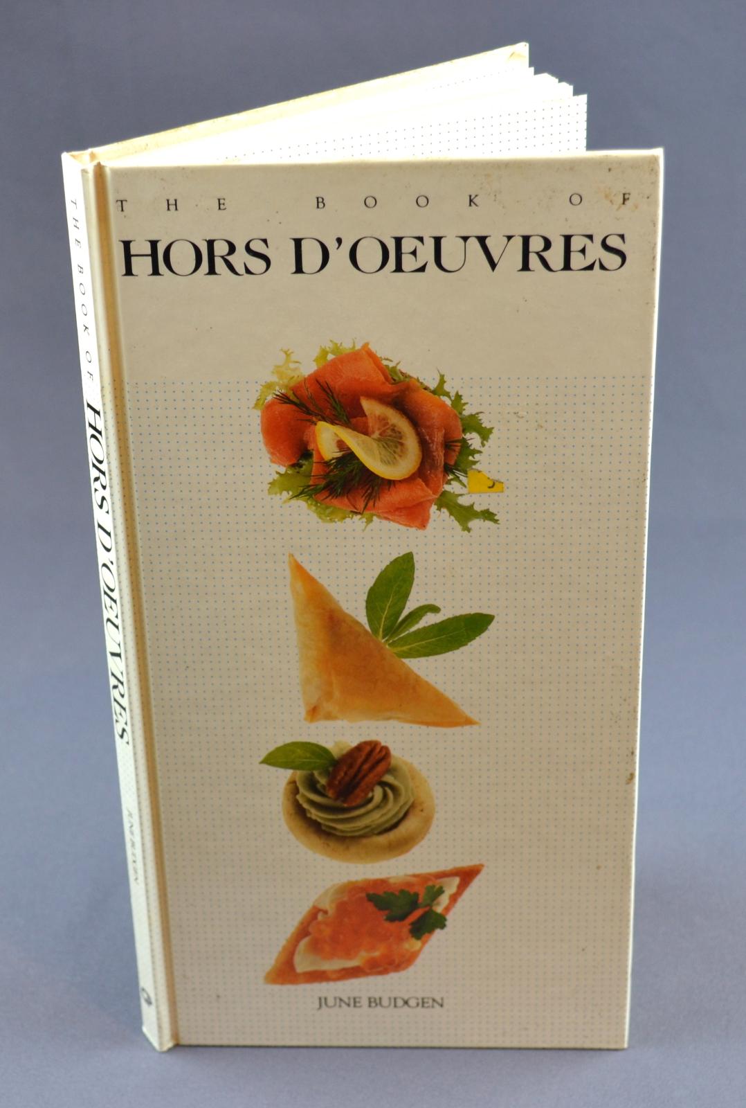 Rectangle hard cover book with a white cover. Black text across top of cover, three colour images of hors d'oeuvres in a vertical row under text