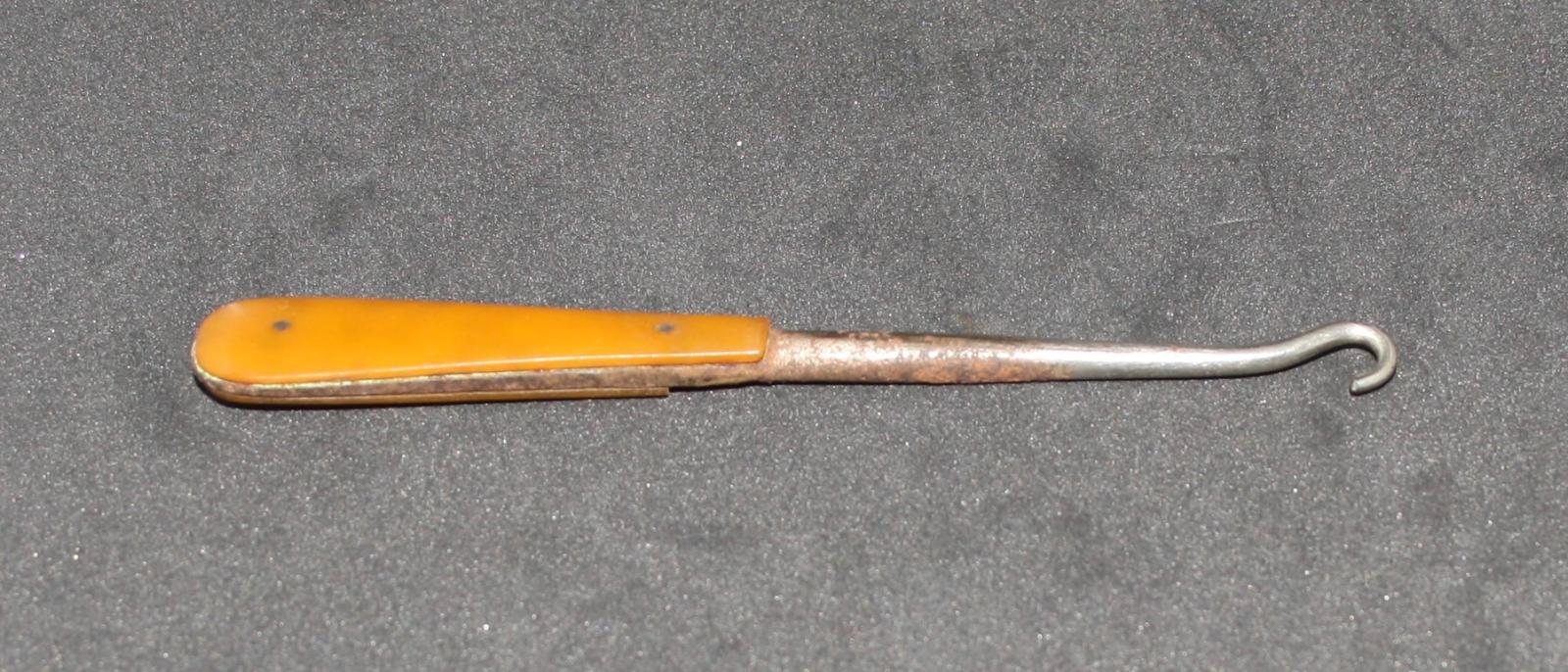 Metal shaft with a hook on the end, yellow tear drop handle at other end