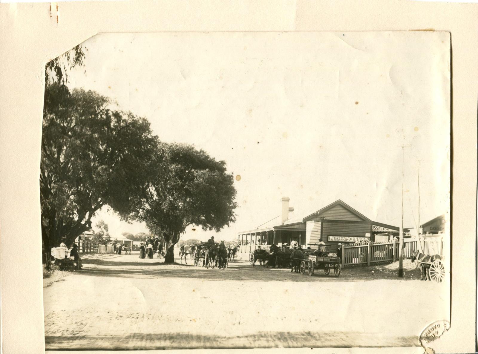 Sepia photograph of Busselton Railway Station building. People on horses and carts stand around the front of the building. 