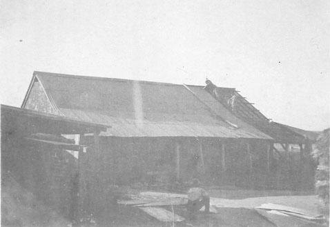 Photograph of men repairing a barn roof