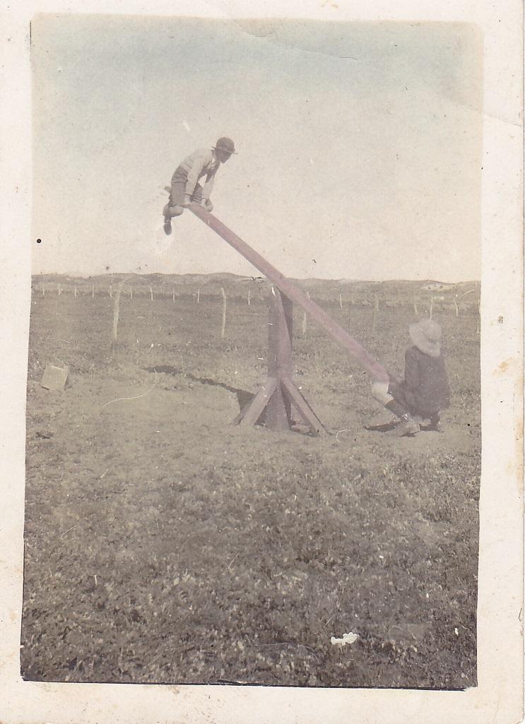 Colour photograph of two boys playing on a see-saw