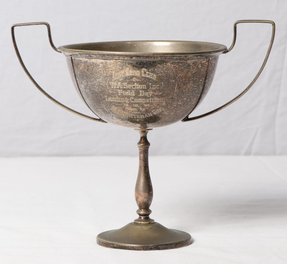 Silver cup with slender base and thin arms, with engraved text in the centre.