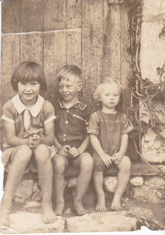 Black & white photograph of three children sitting on a step.