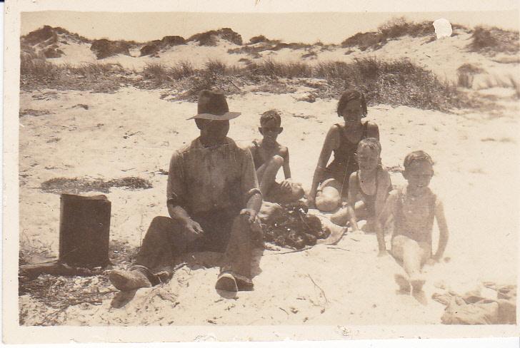 Black & white photograph of a man and children at the beach