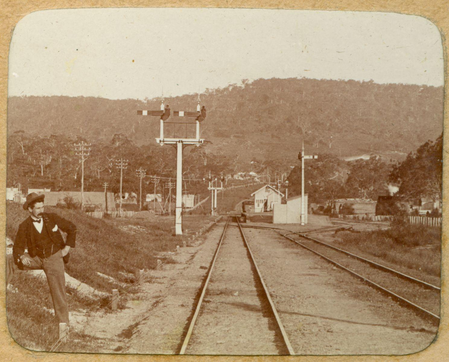 P100-09. Bellevue Railway Station viewed from the railway line to the west and looking east to the Perth hills. The man in the left of the image is photographer William Dennis Dawson.