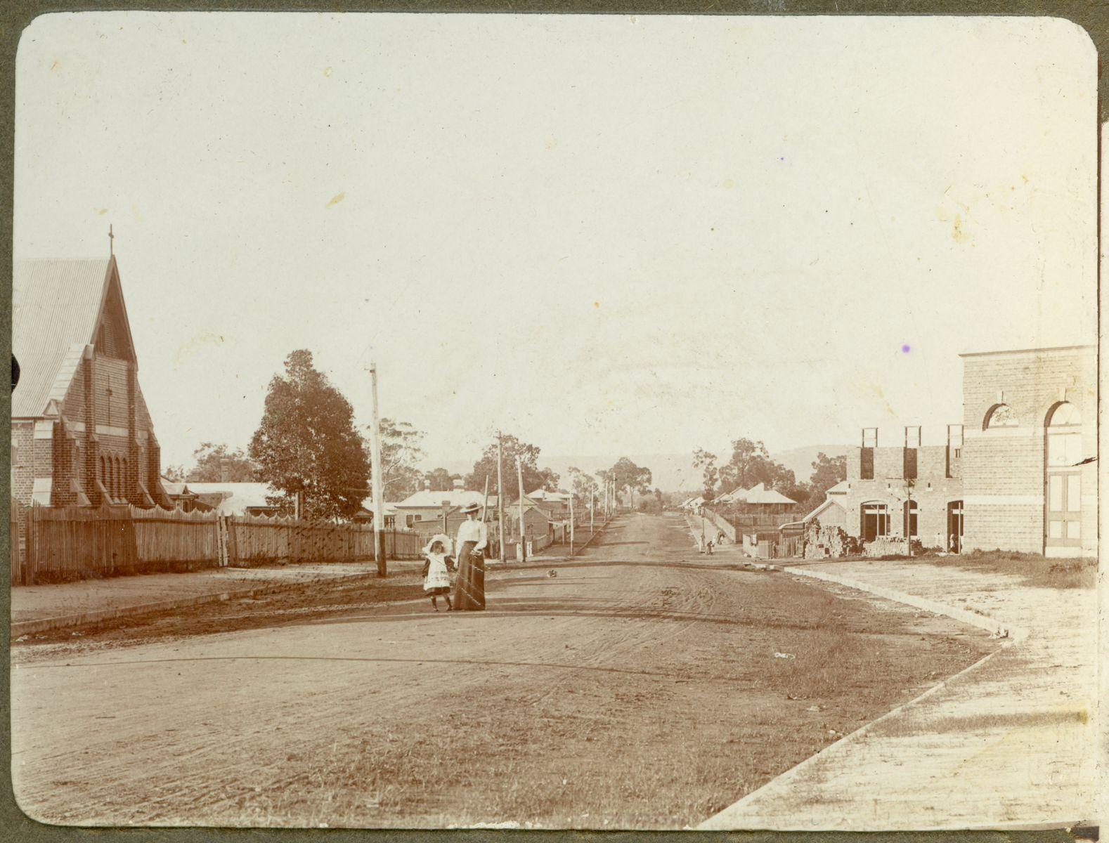 P100-13. Newcastle Road (Great Northern Highway), looking north-east. The Church of Ascension is on the left and on the right is the public hall and behind that the Council Club Hotel is under construction.