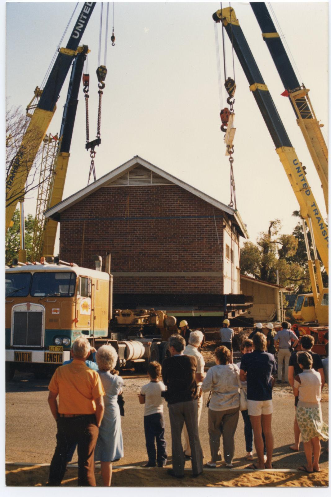 The four cranes lowering the school on to the trailer ready for transport