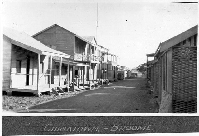 Black and white landscape photograph of buildings each side of the street. 