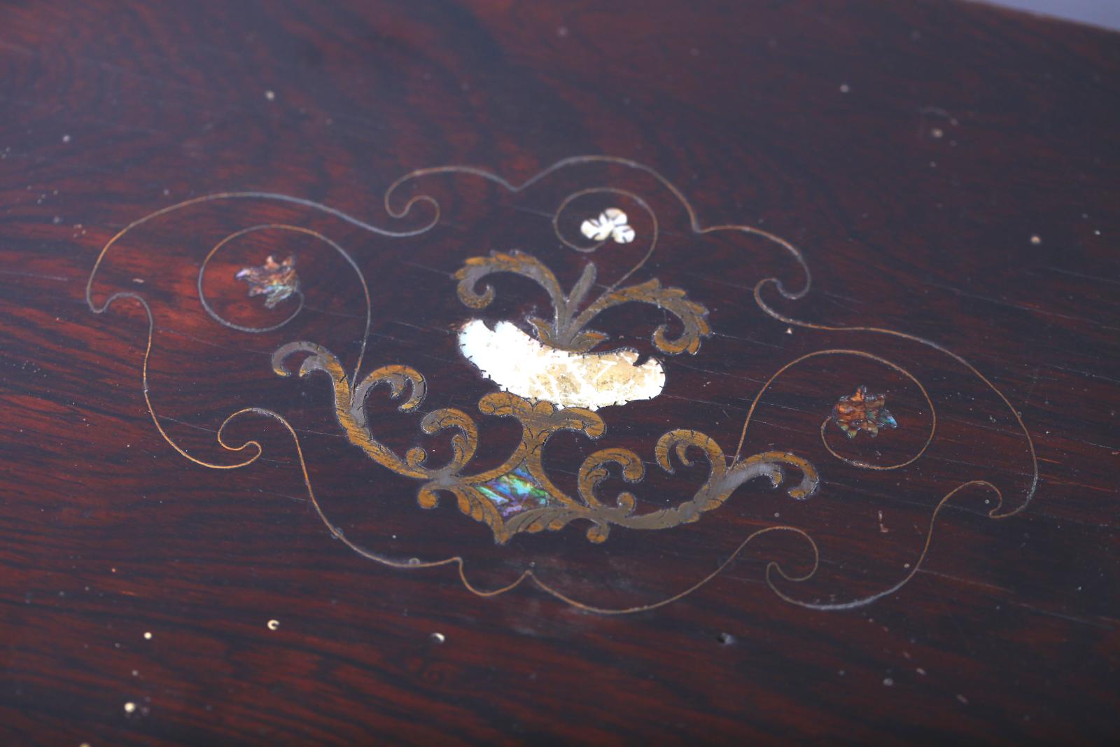 Image showing the top of a rectangular wooden box with a close up view of the lid, which has  an inlay of mother of pearl and copper in a floral pattern