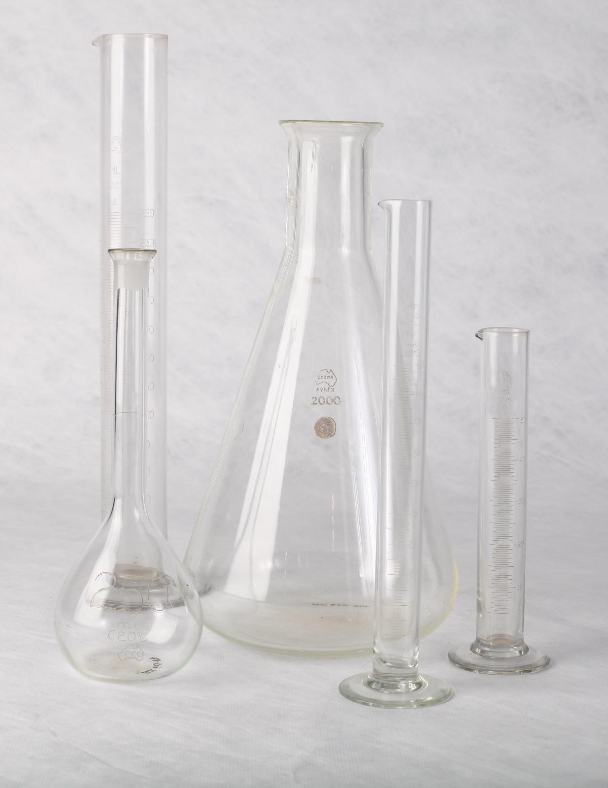 Cylindrical glass container shown in a collection of four glass flasks