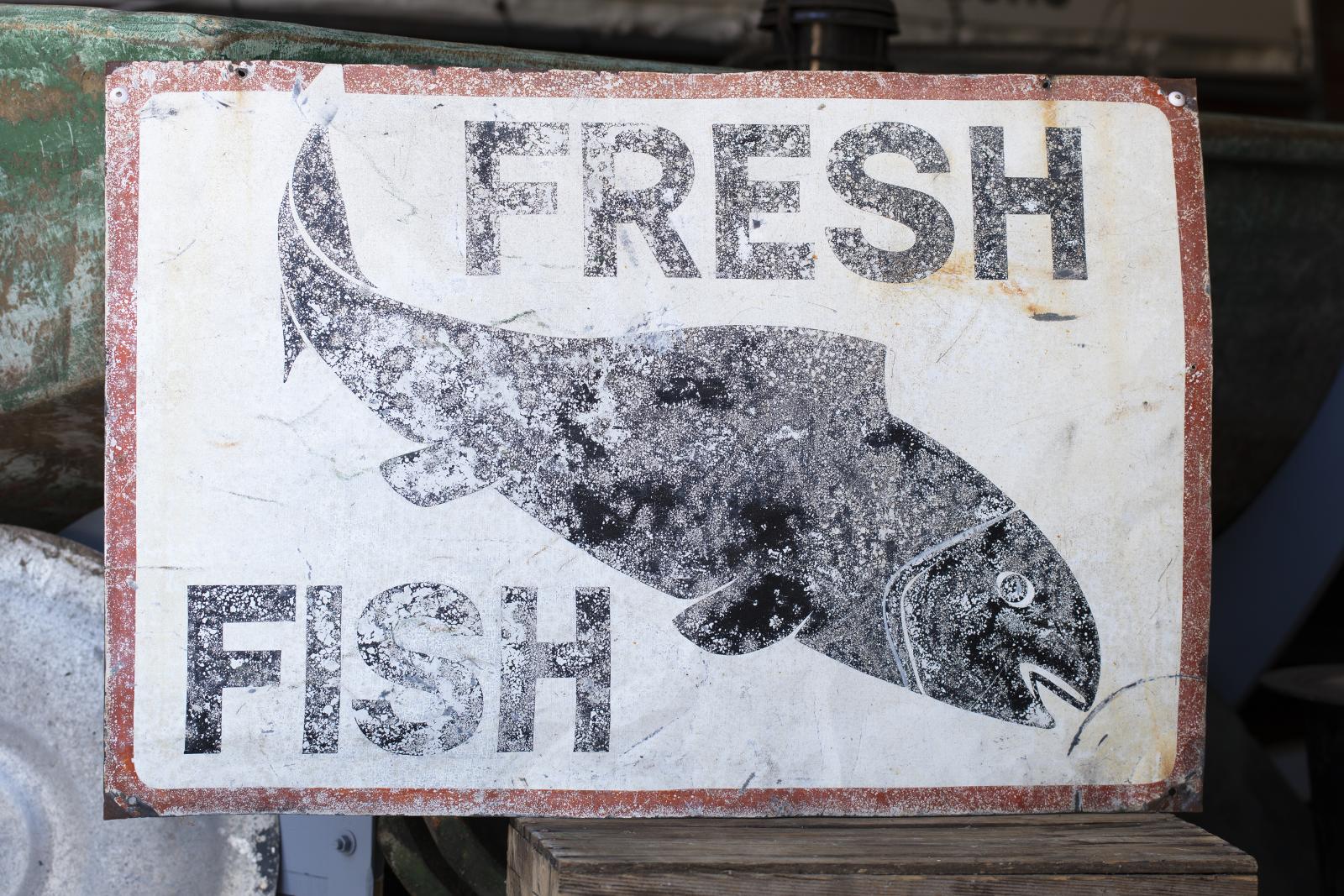 Sign with the words 'fresh fish' on it, surrounding the silhouette of a fish