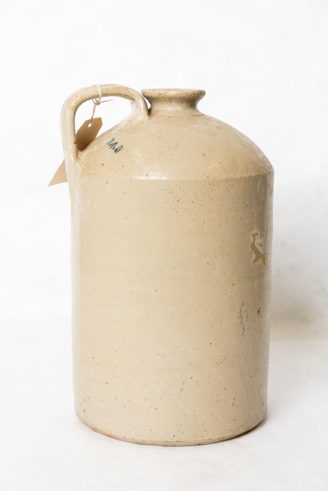 Stoned coloured ceramic jug with handle on the top near the spout. The top of the jug tapers to a narrow spout.