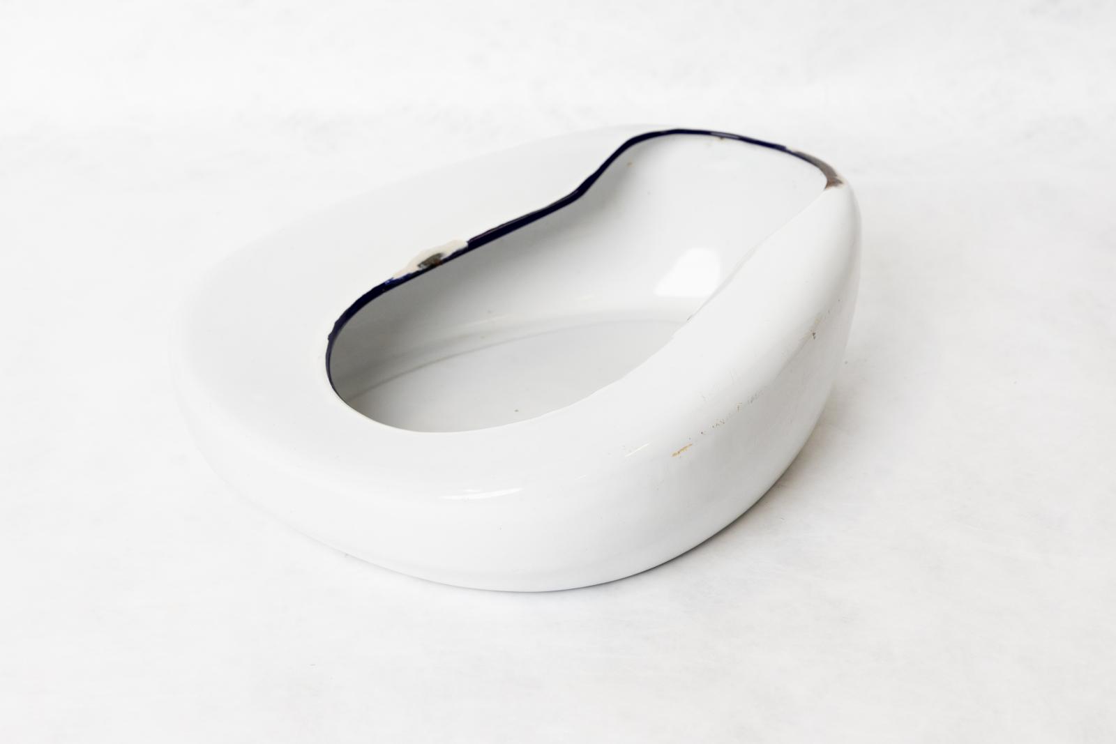 A white bed pan with a black inner rim