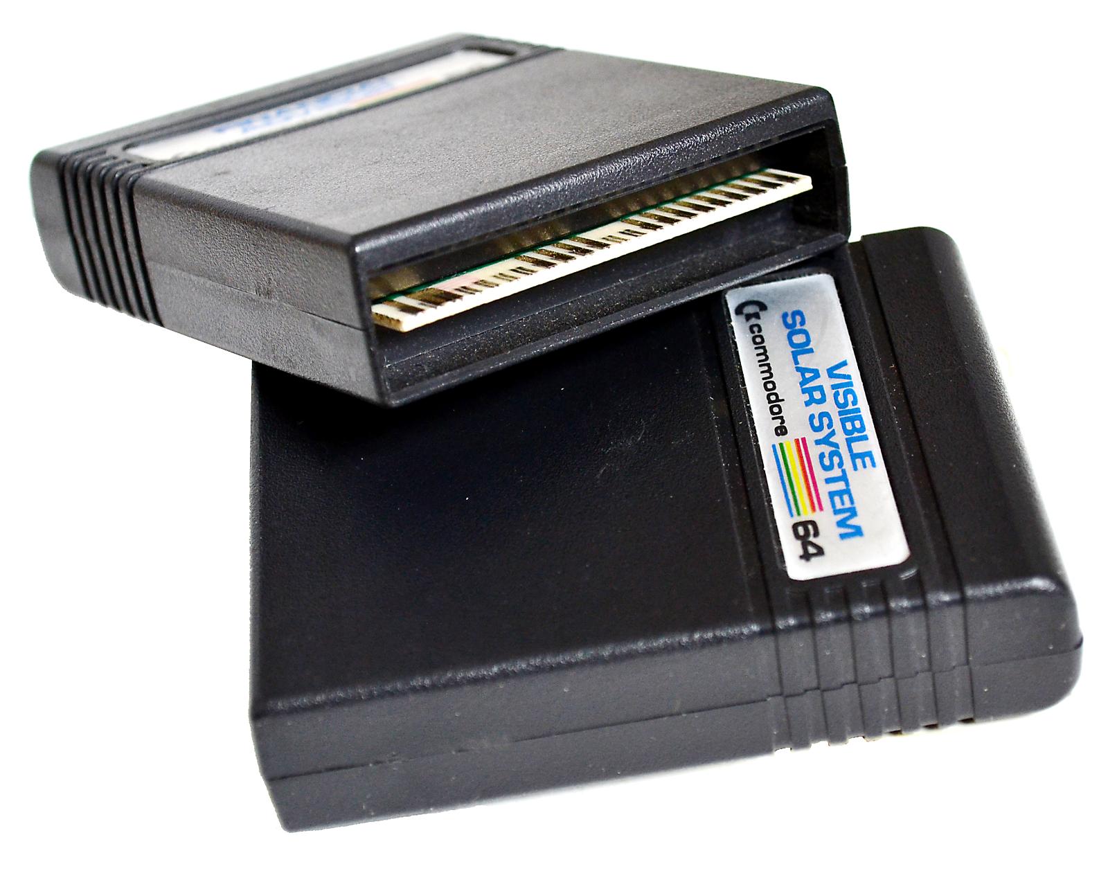 Two black oblong cartridges for use in Commodore 64. One has visible label of "Visible Solar System"