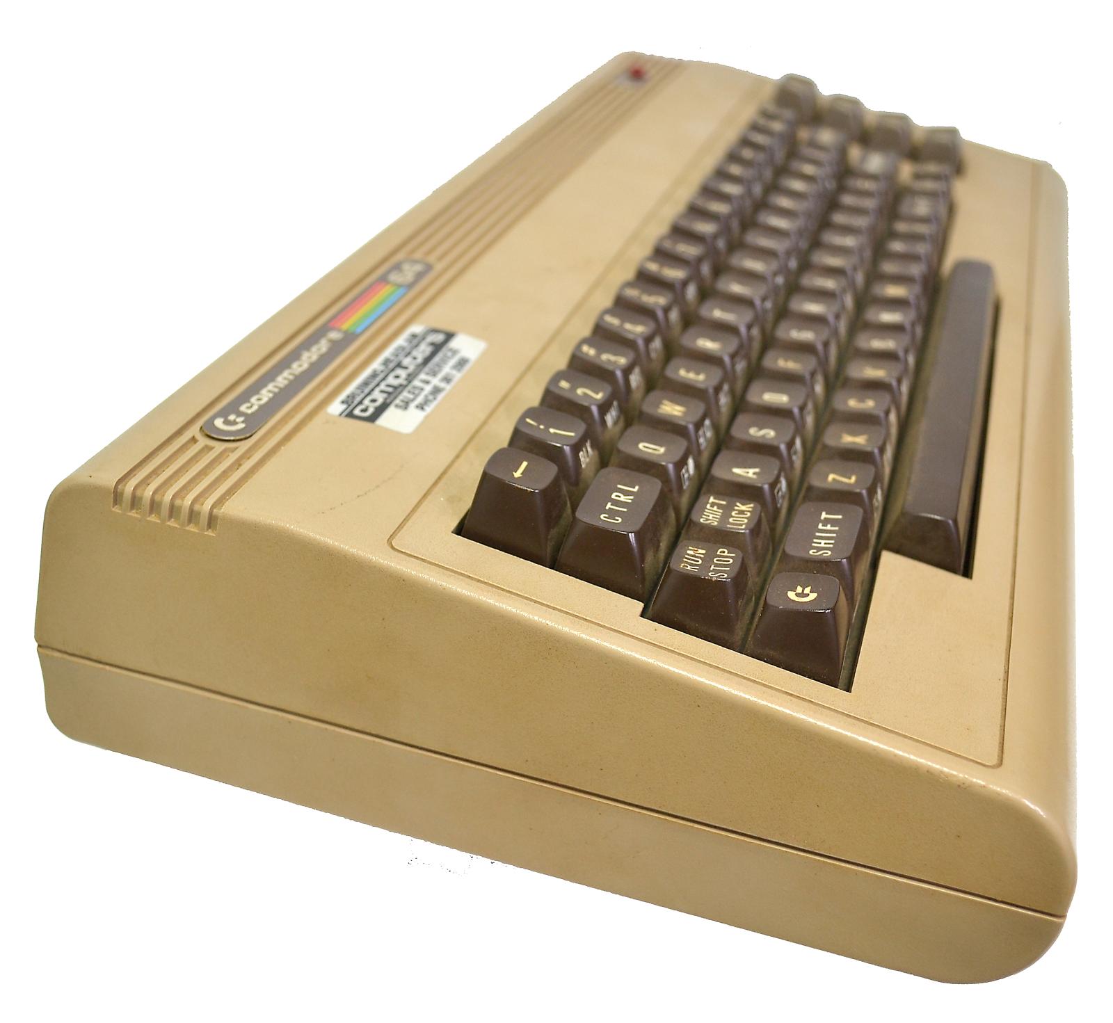 Side view of Commodore 64 computer console, shows a keyboard with 4 rows of keys. Console tapers from the back to the front