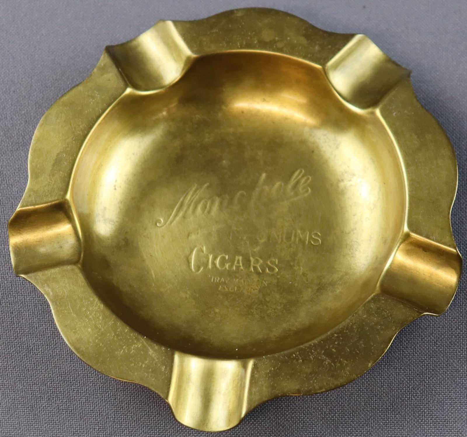 Round brass flat ashtray with circular indentation in the middle and a flat base. Text stamped in centre of ashtray 'Monopole Magnus cigars Tray Made in England. Five indentations on rim to rest cigaretts