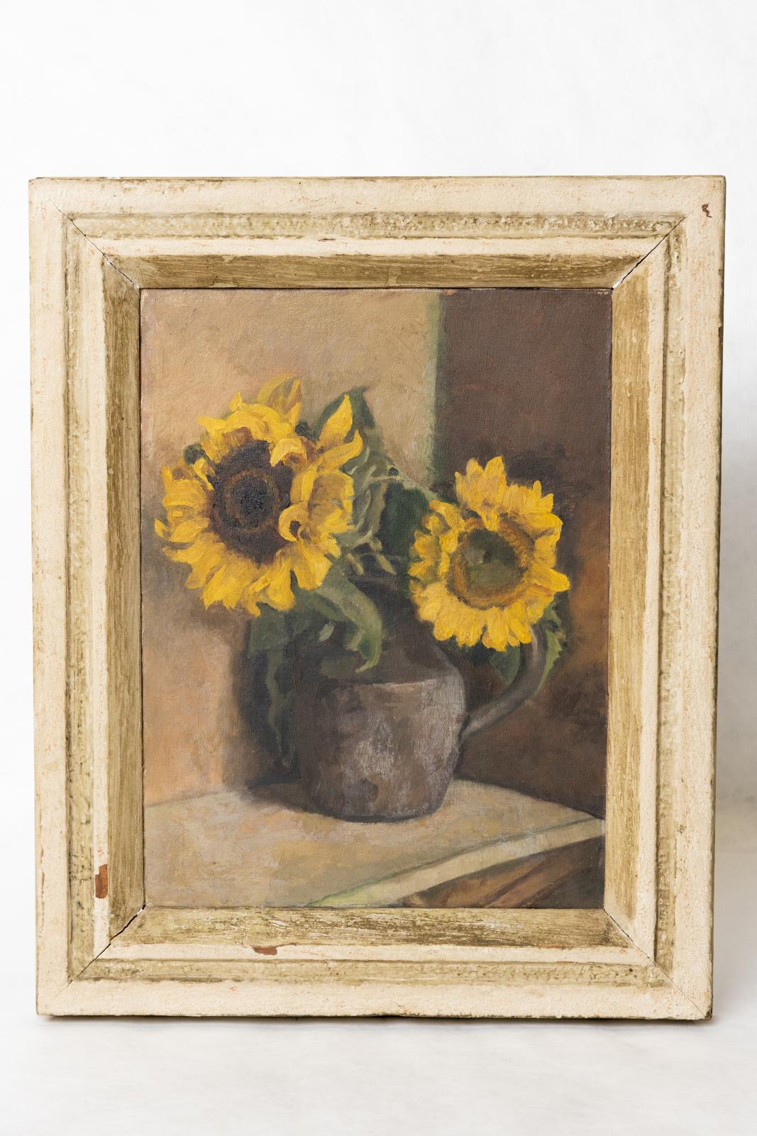 Cream painted frame, paint is worn and damaged in some areas. The painting is a separate canvas fit into the frame. Two sunflowers in a brown jug with handle, placed on a white/cream table top, against a cream and brown wall.