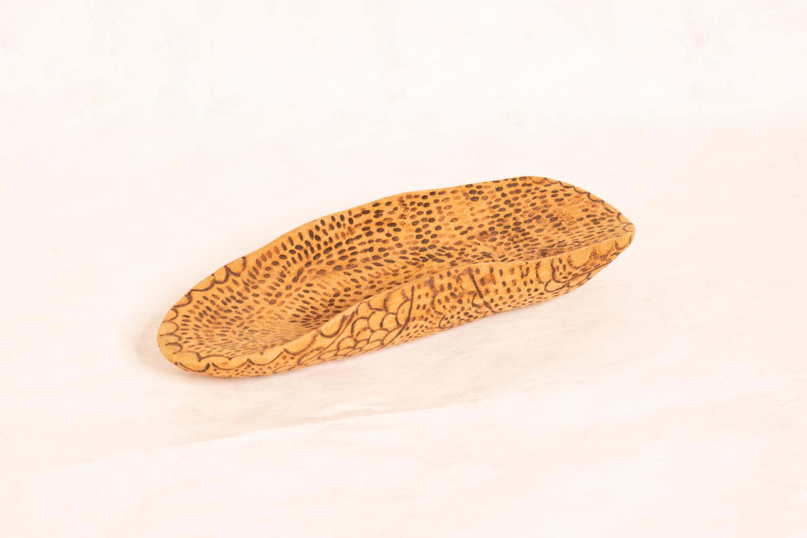 Carved beige wooden dish, Yandi, with rounded ends, curved up sides and flat base. Small lines, circles and dot patterning burnt into inside and outside surfaces.