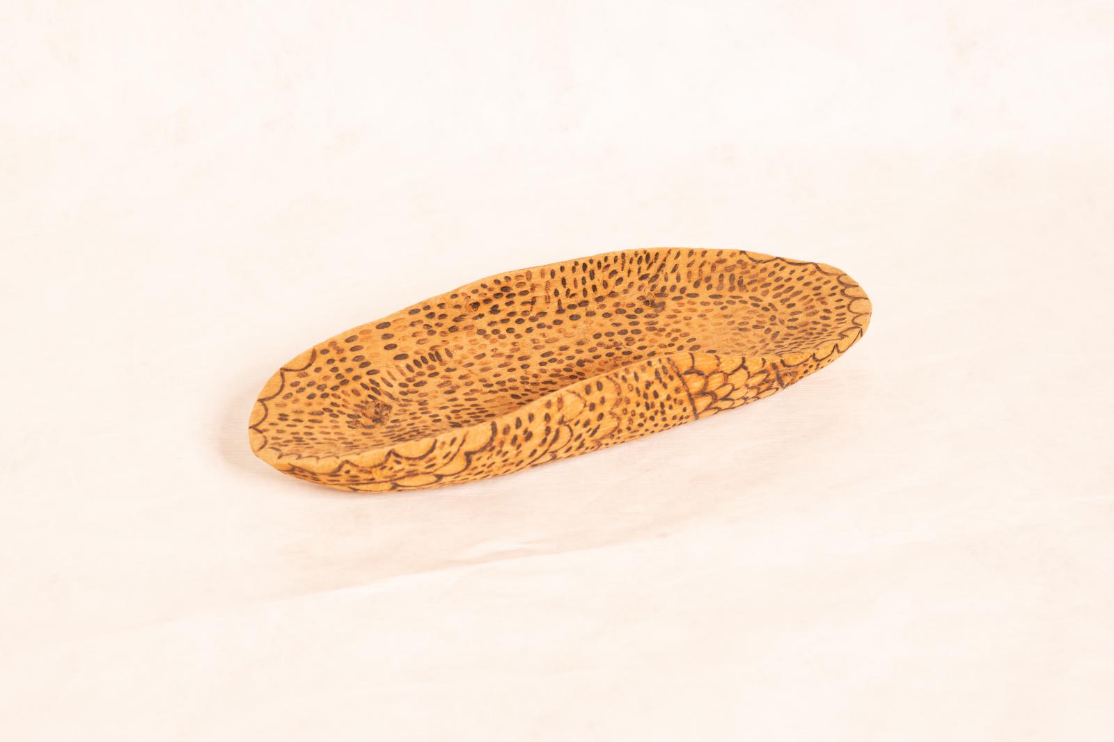 Carved beige wooden dish, Yandi, with rounded ends, curved up sides and flat base. Small lines, circles and dot patterning burnt into inside and outside surfaces.