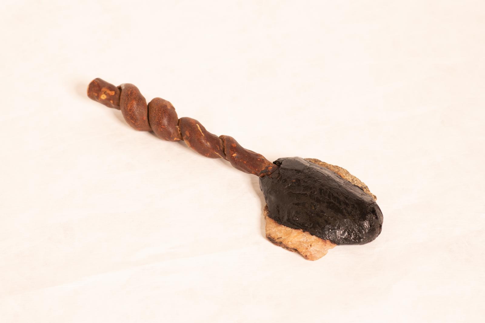 Ceremonial stone axe with twisted vine handle and two carved stone heads attached to handle with resin.