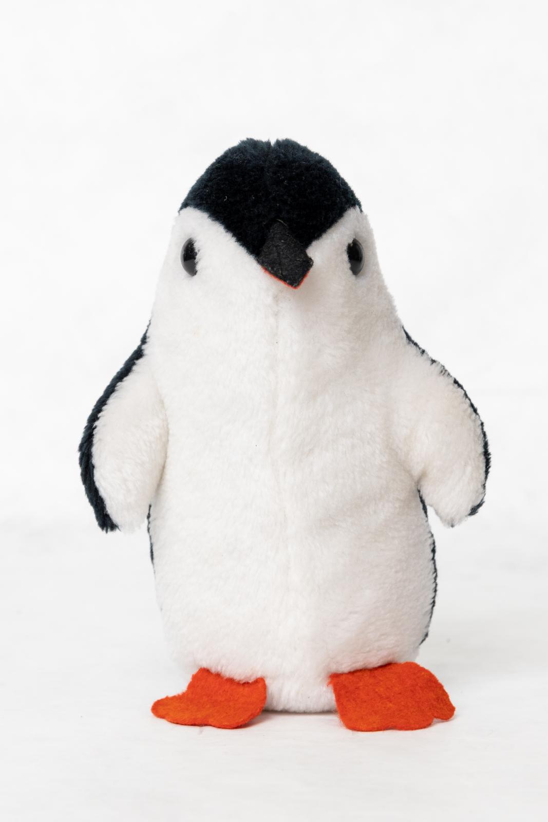 A penguin toy made of black and white faux fur fabric. Front side is in white fabric, whilst the back is in black. The feet and mouth opening are made of red felt. The mouth has a black upper as well in felt fabric. Two plastic black buttons are sew in place for eyes.