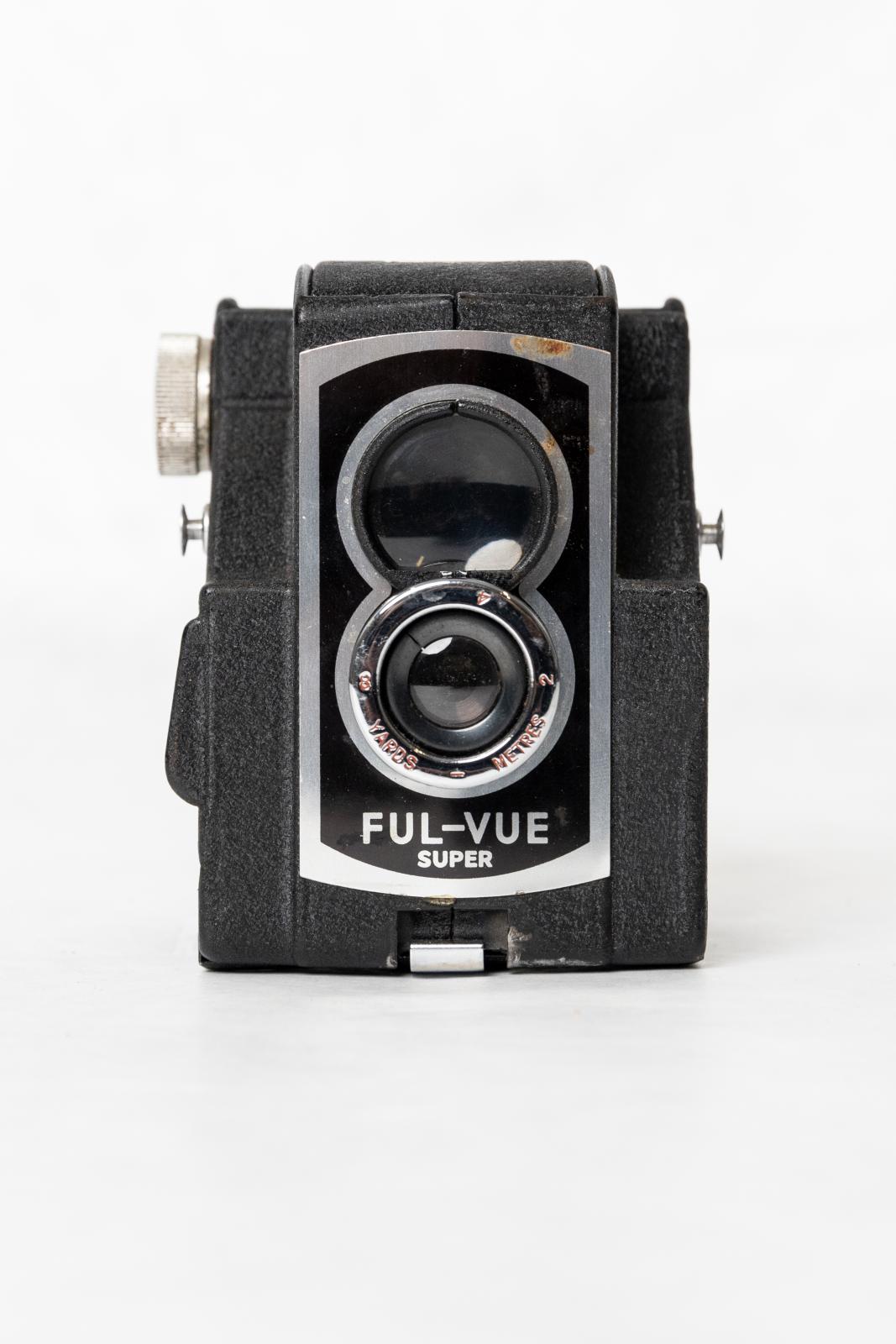 A black, plastic-coated box with a silver metal edged rectangle on the front. Underneath this lens, printed onto the surface of the rectangle in silver letters is 'FUL-VUE/ SUPER'. There is also a brown leather camera case, the top opens from a front flap, and fastens to the base with a small, gold coloured metal clasp.