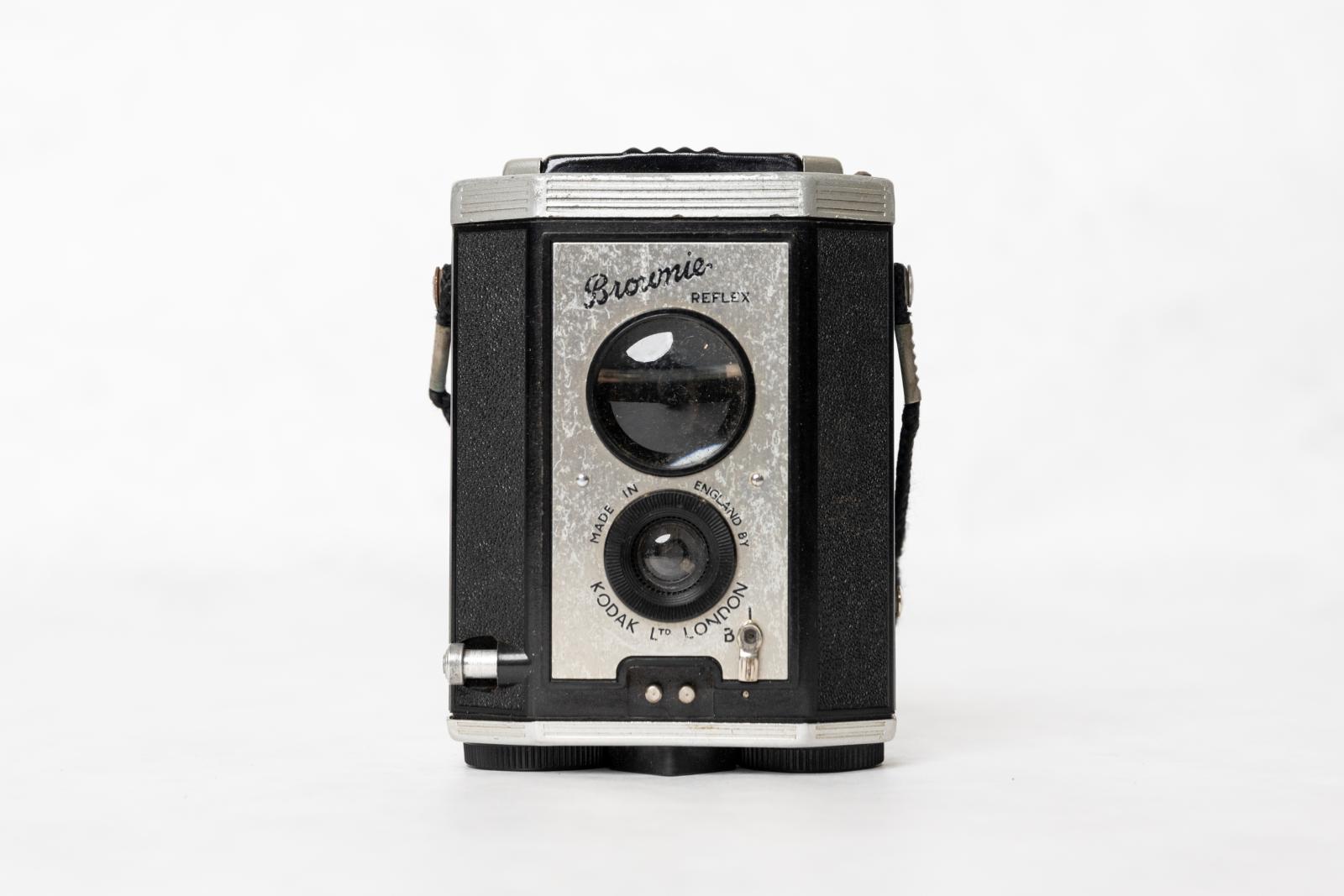 A rectangular black and silver Brownie Kodak Camera. There are two circular glass lenses on the front.