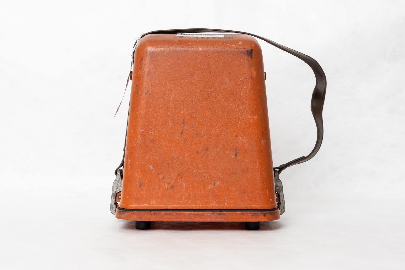 An orange rectangular lid with a strap attached