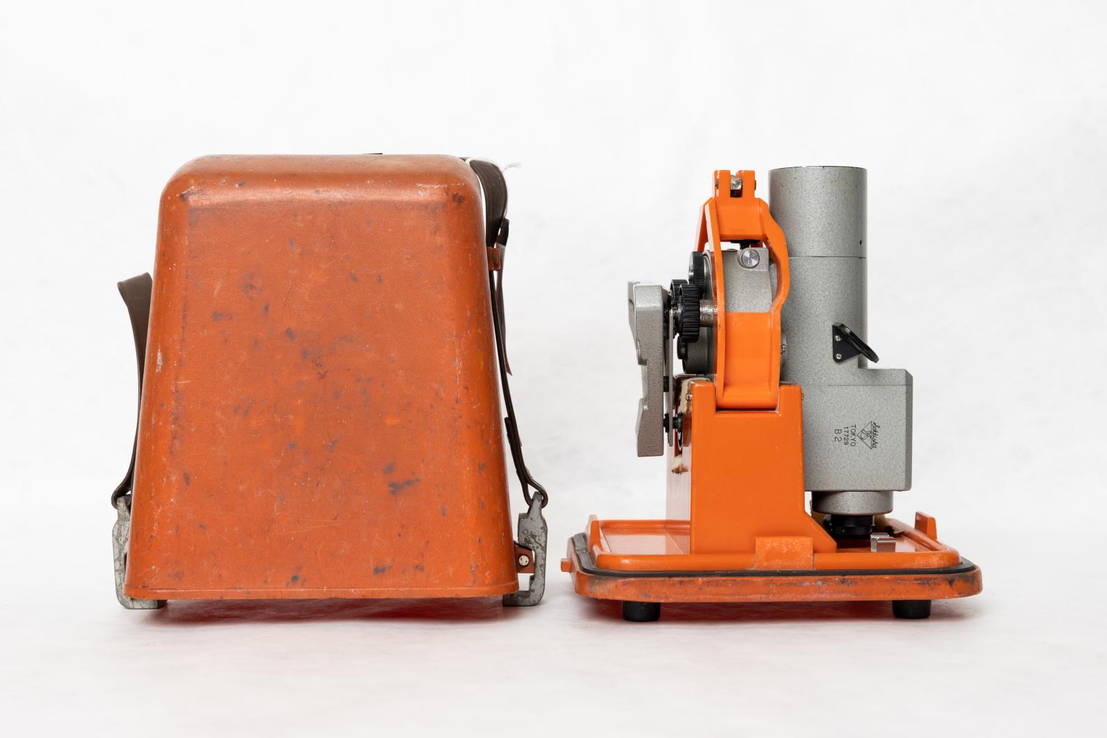 An orange, rectangular lid next to an orange and silver measuring device.