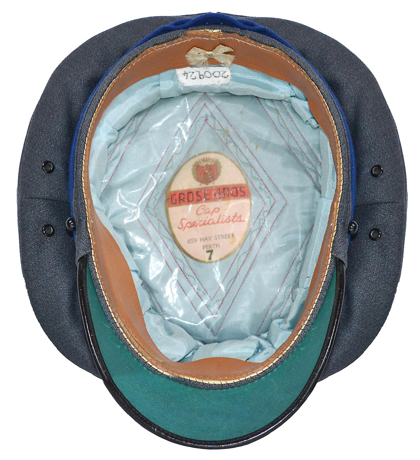 Stationmaster's Cap showing the inside of the cap. A brown leather band is on the inside of the cap, with pale blue cloth lining inside the cap. A sheet of plastic covers the cloth lining. a paper label giving makers information, "Grose Bros" and cap size is in the middle of the inside cloth.