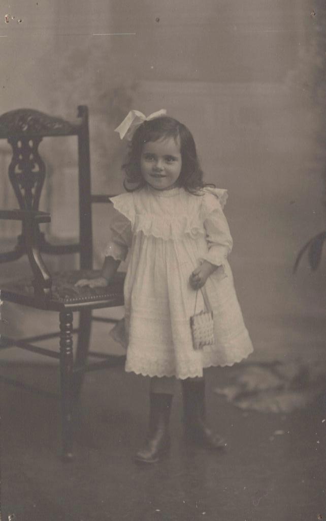 black and white photo of a young girl learning on a chair