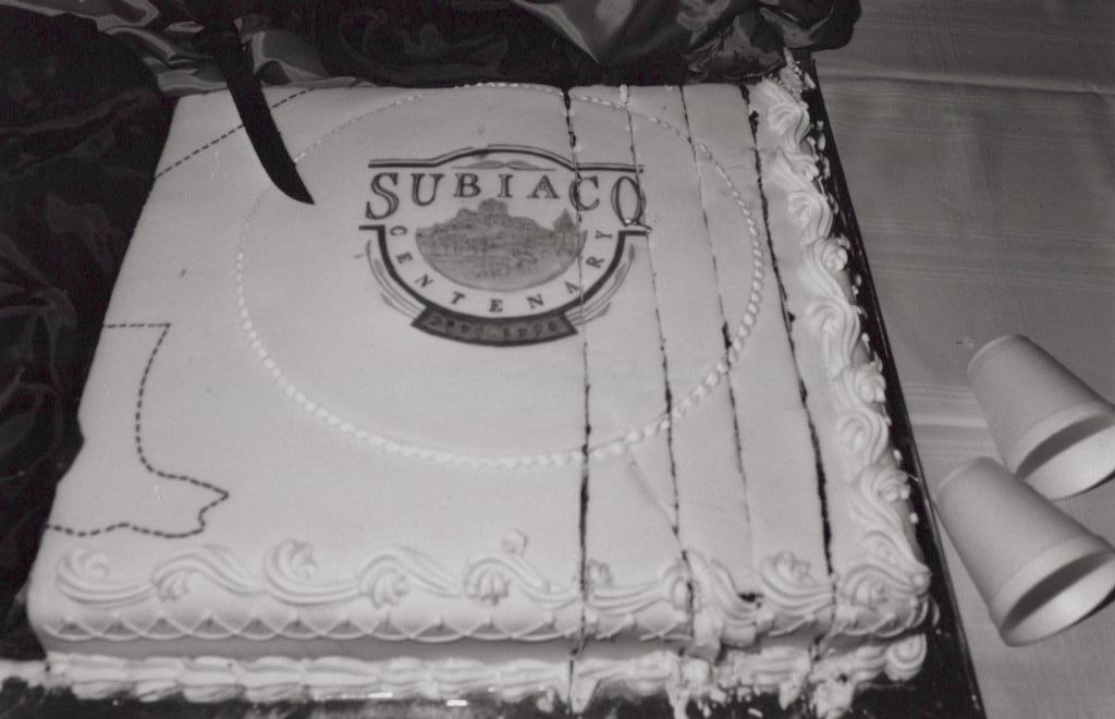 black and white photo of a cake. The cake has writing on it 'Subiaco CENTENARY'