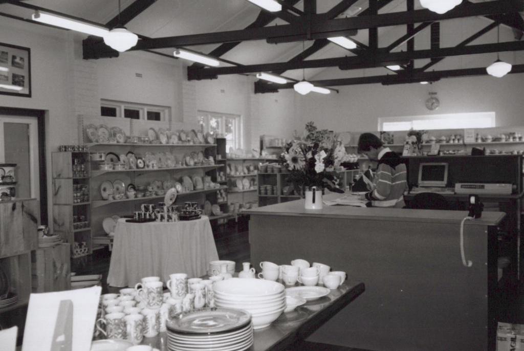 black and white photo of a woman behind a counter in china shop