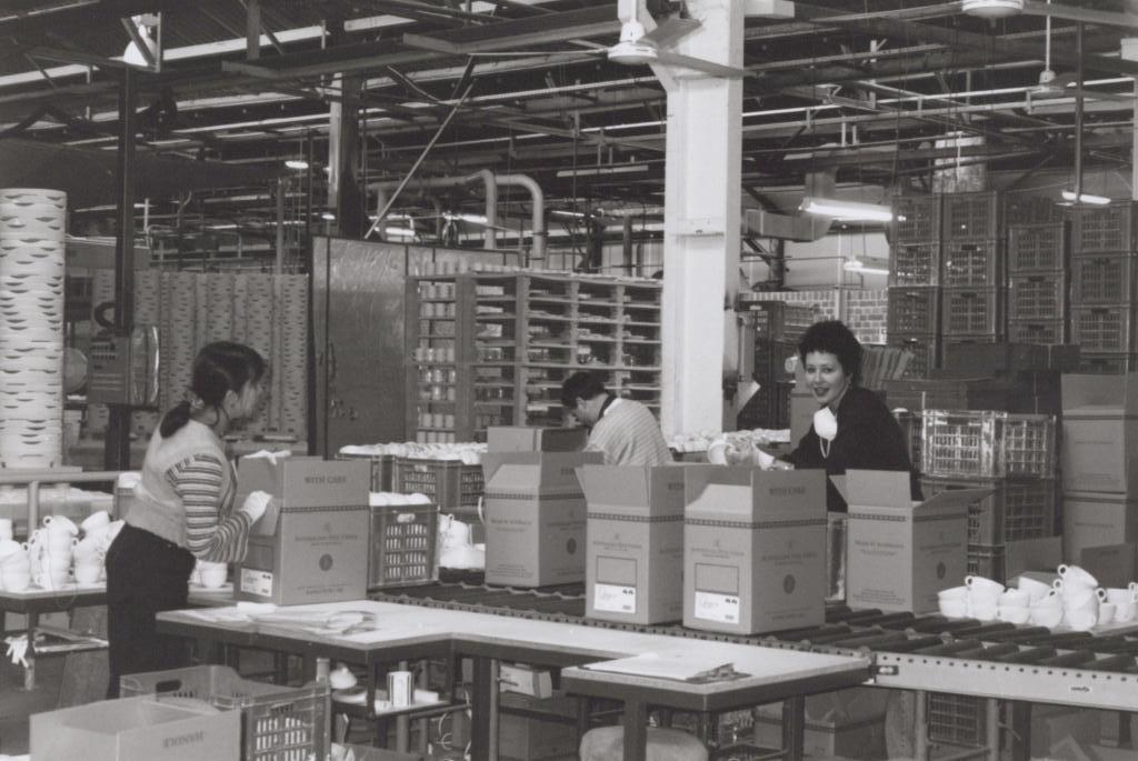 three people packing boxes inside a factory