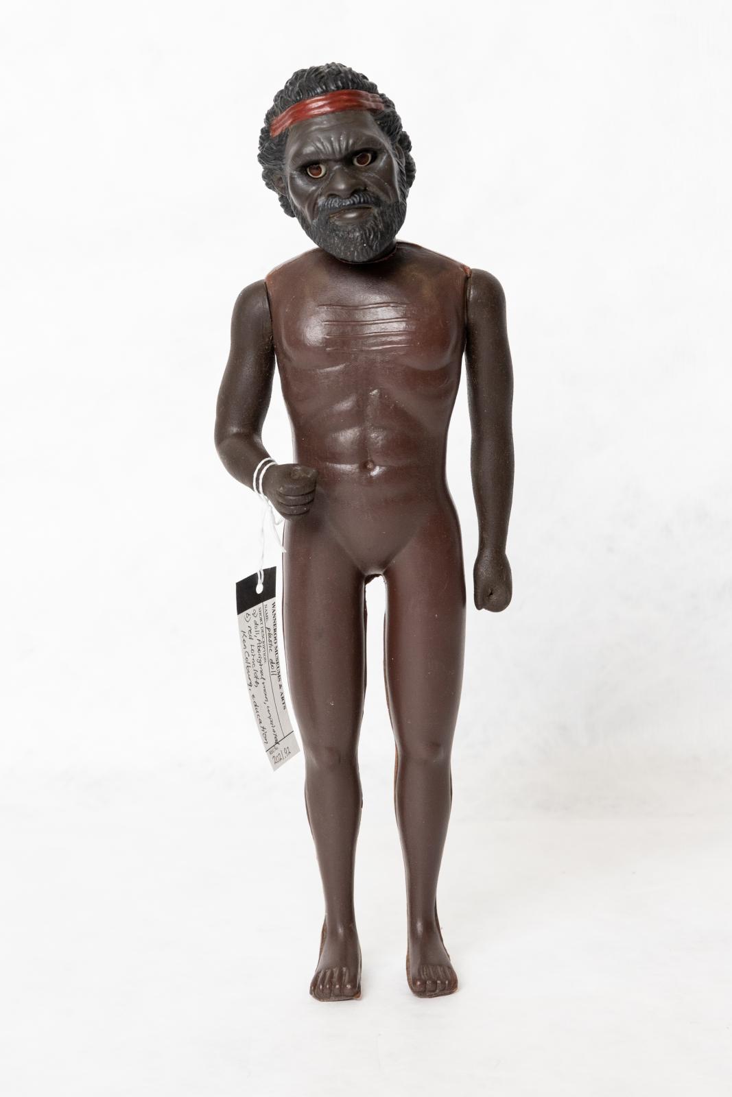 An Aboriginal adult male doll. The doll has not been painted, he only has a red headband and no clothes.   