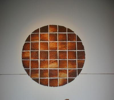 Ceramic sculpture temporary image depicting a burnt orange coloured circle with a grid pattern lined in white