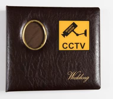 Brown, bound vinyl cover wedding album with yellow CCTV sign in upper right corner of the cover and yellow text "Wedding" in italics in the lower right corner.  