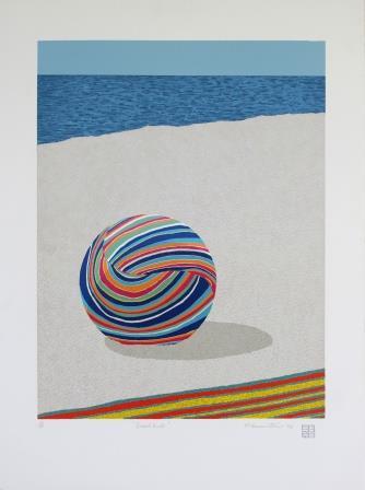 Multicoloured beach ball on white sand with ocean in the background