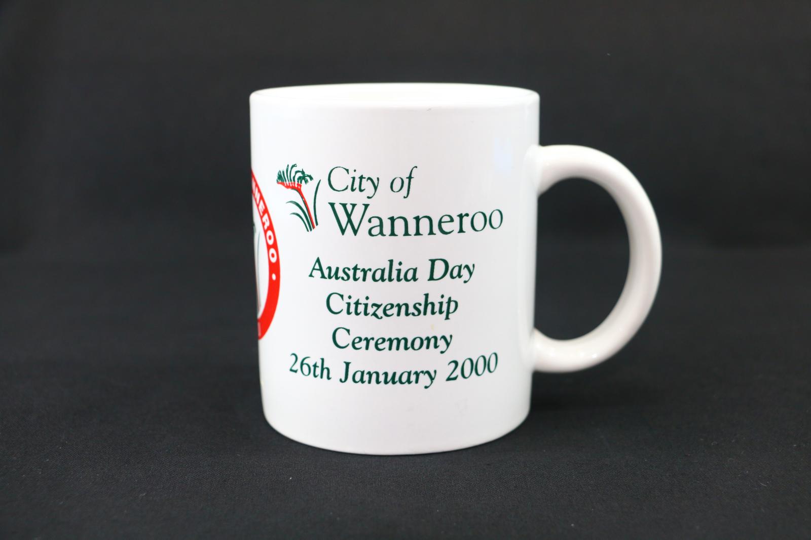 A round, white ceramic, City of Wanneroo, mug. With text which states 'City of Wanneroo/ Australia Day/ Citizenship/Ceremony/26th January 2000' in green. 