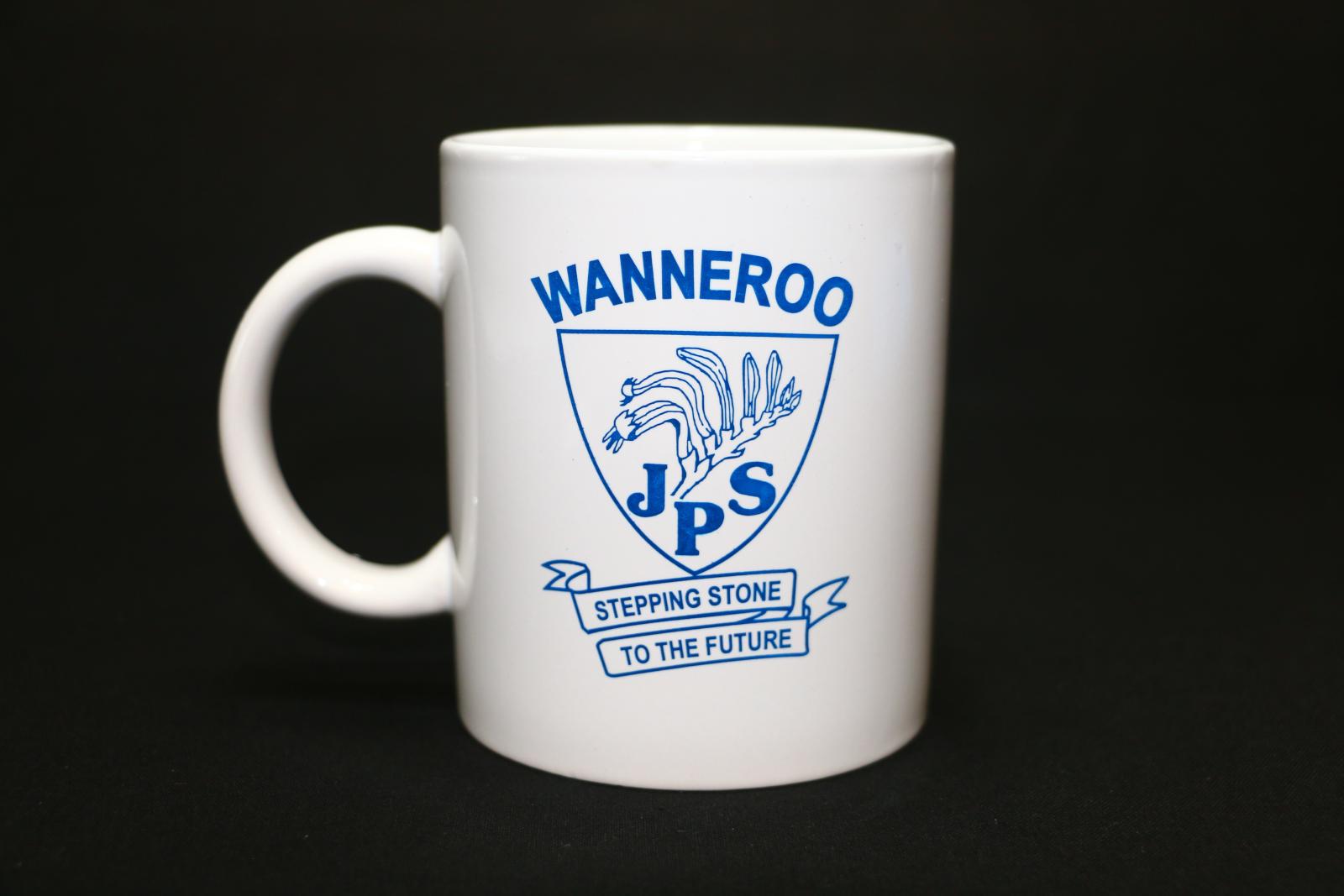 A white ceramic, Wanneroo Primary School, mug. On one side of the mug is a school emblem in dark blue ink. Written across the top in thick letters is 'WANNEROO'. Underneath is the outline of a shield. In the shield is a Kangaroo Paw flower motif with 'JPS' written underneath in bold letters. Underneath the shield is a scroll with 'STEPPING STONE/TO THE FUTURE' written on it.