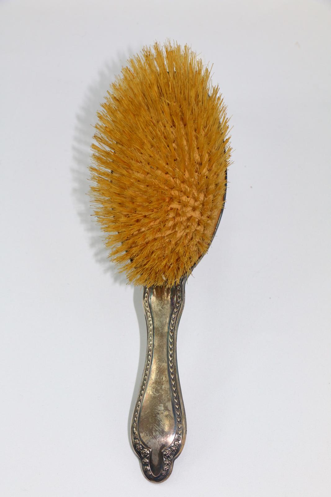 The front of a silver hairbrush.