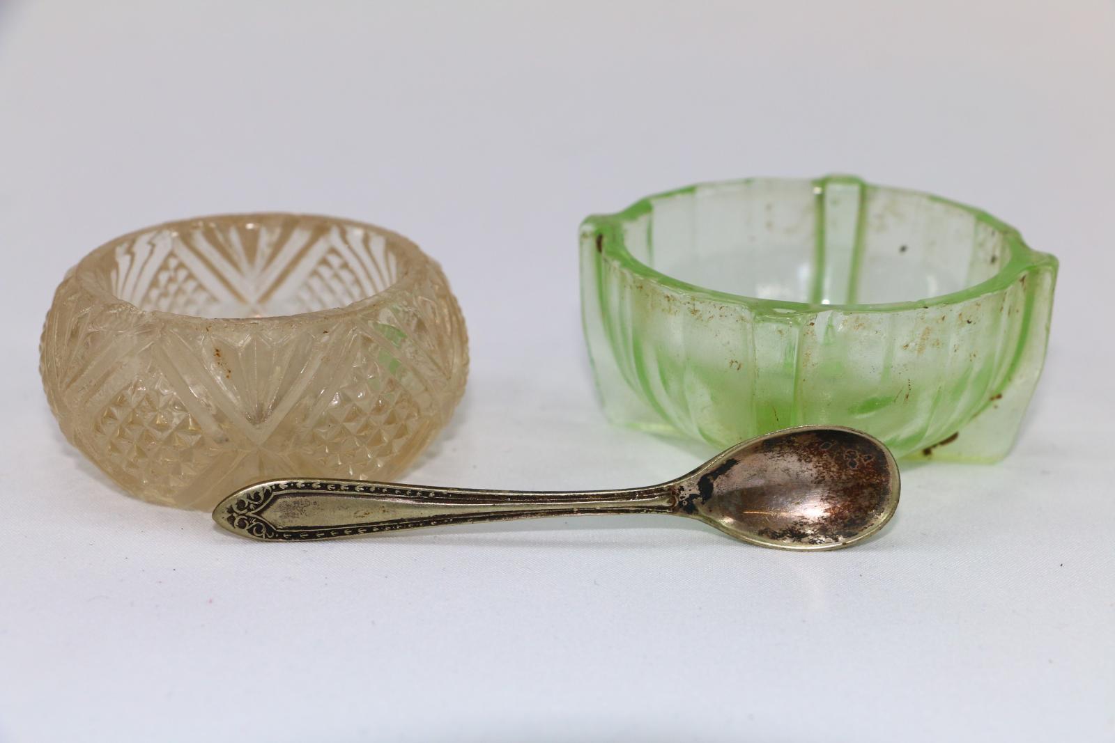 A small patterned clear glass bowl, a small patterned green glass bowl, and a small silver metal teaspoon. 