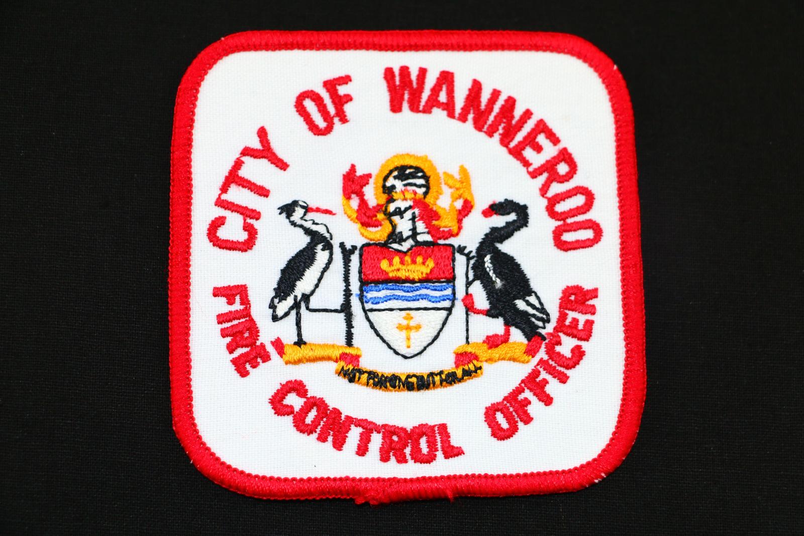 A square City of Wanneroo cloth badge. The badge is white and edged in red thread, 'CITY OF WANNEROO FIRE CONTROL OFFICER' is embroidered in a circular shape around the Wanneroo crest.